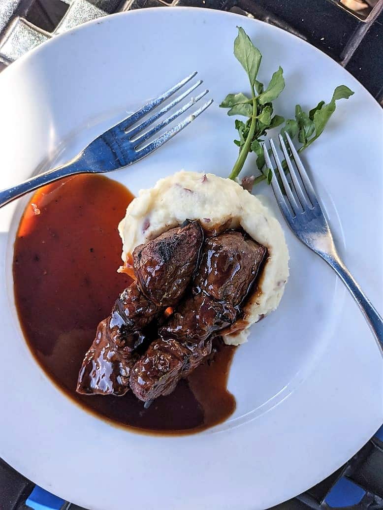 top down view of steak sitting on mash potatoes and au jus