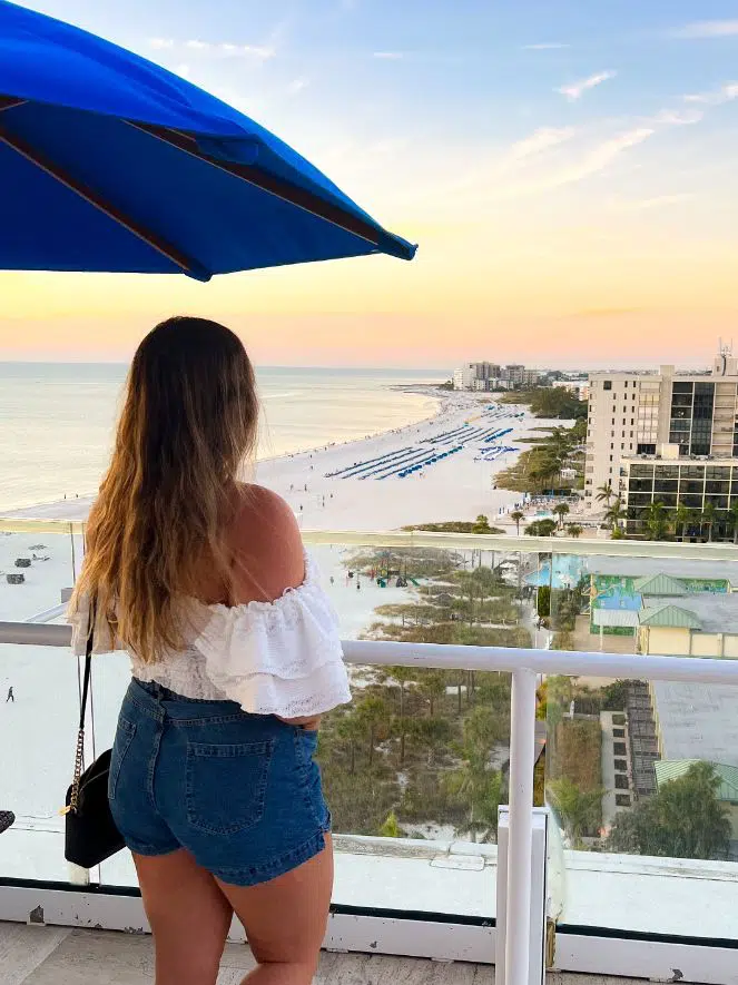girl in white off the shoulder top looking at st pete beach during sunset from spinners restaurant