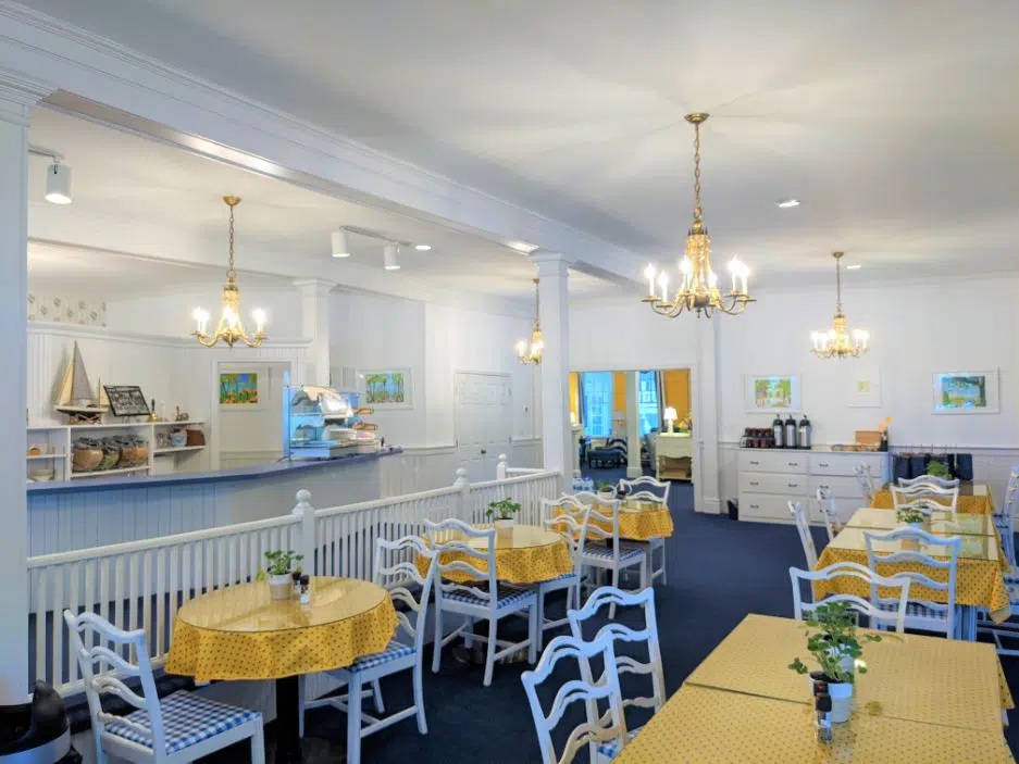colonial style hotel dining room with white walls, white chairs, and yellow table cloths