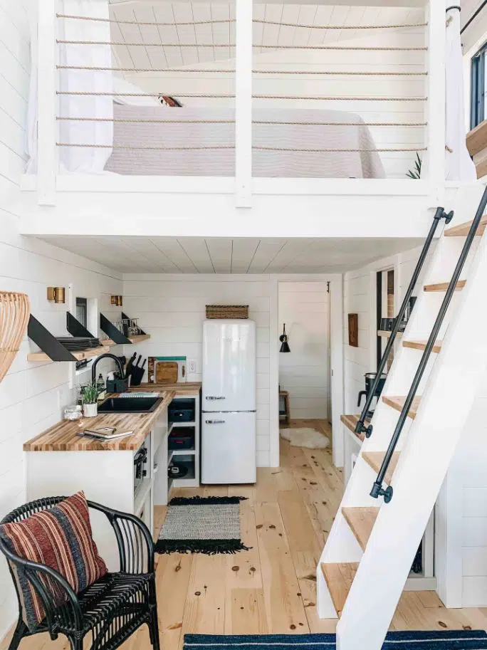 inside of a houseboat mini stacked fridge and kitchen with white walls and latter to attic with bed