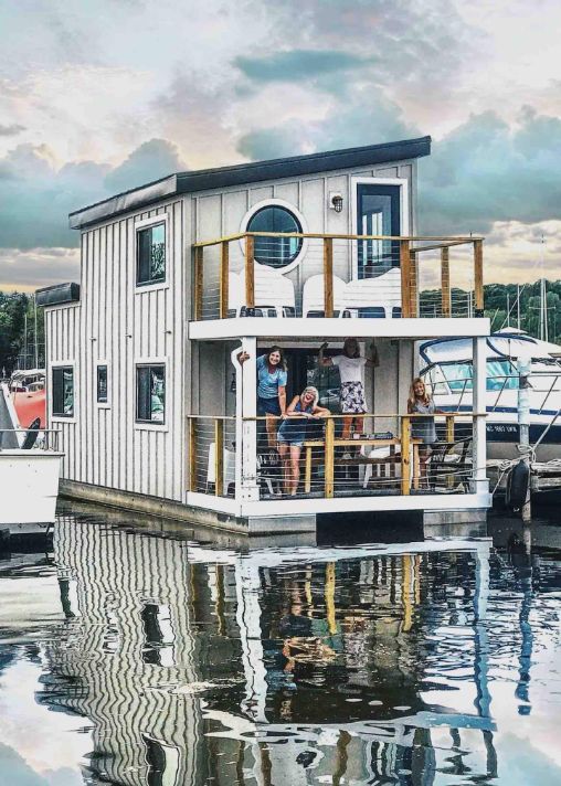 white two story floating boat house with small upper and lower deck