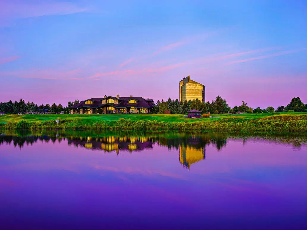 purple sunset sky reflecting into lake with tower hotel and golf club building