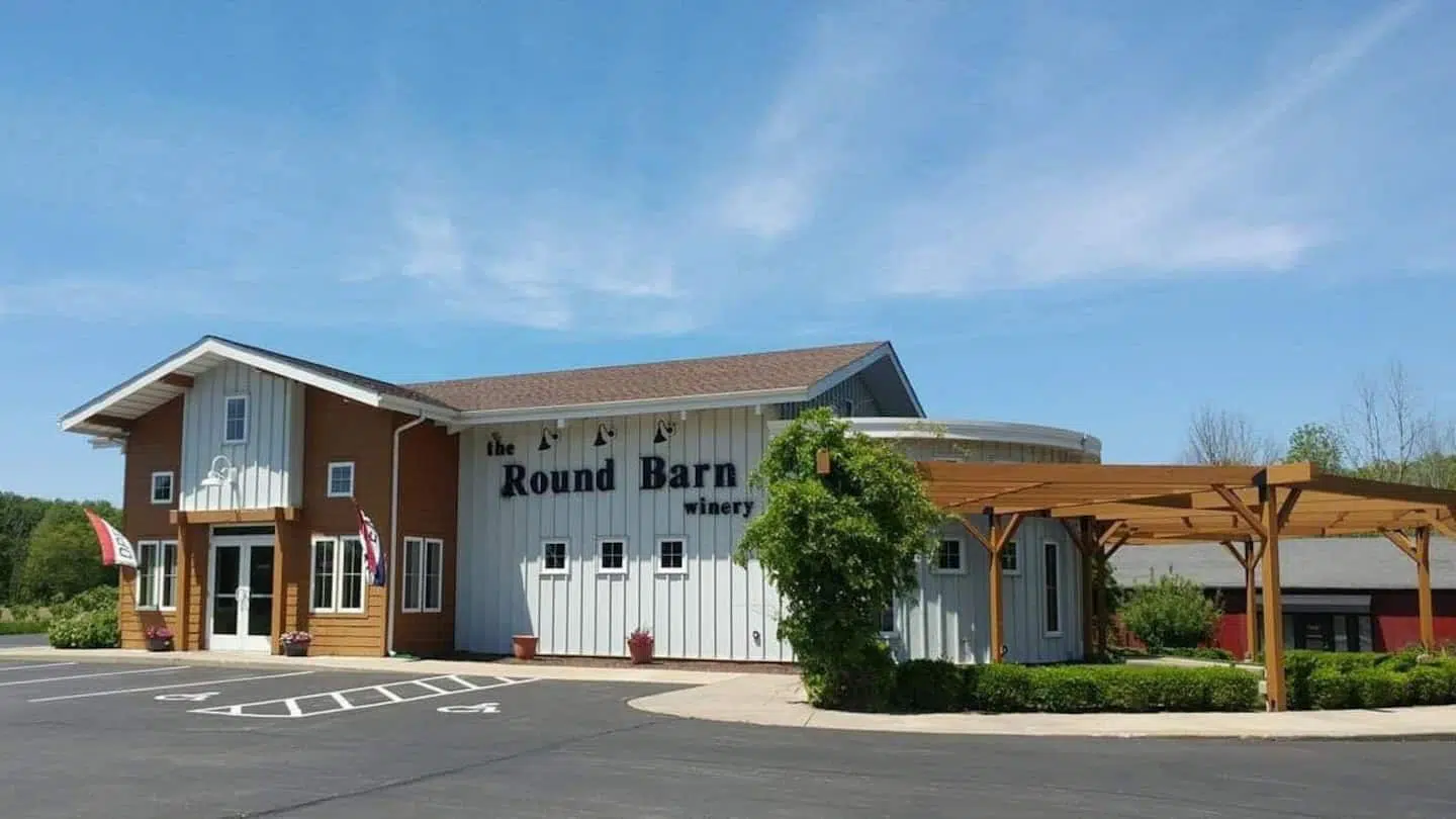 wood and white house shaped building with circular attachment and outdoor patio with bushes