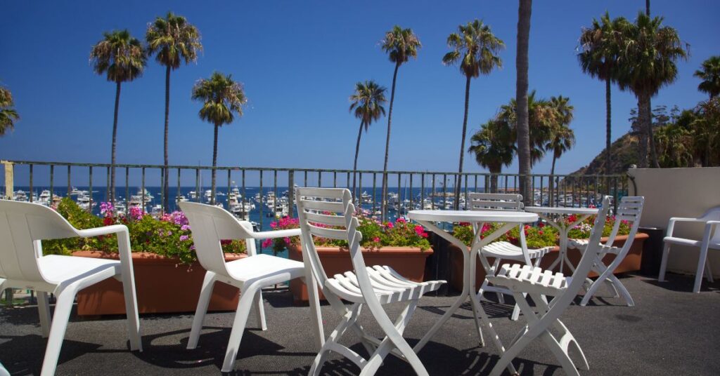 Catalina island resort observation deck with white chairs and table and a view of palm trees and the harbor filled with boats