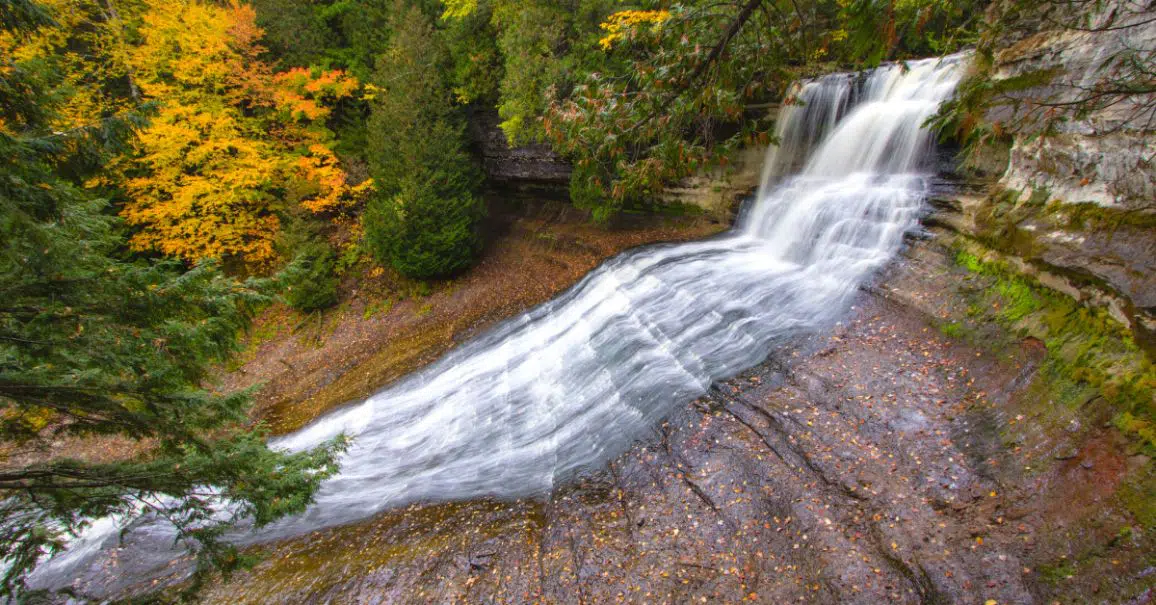 side view of Laughing Whitefish Falls in upper Michigan with fall colored trees surrounding it