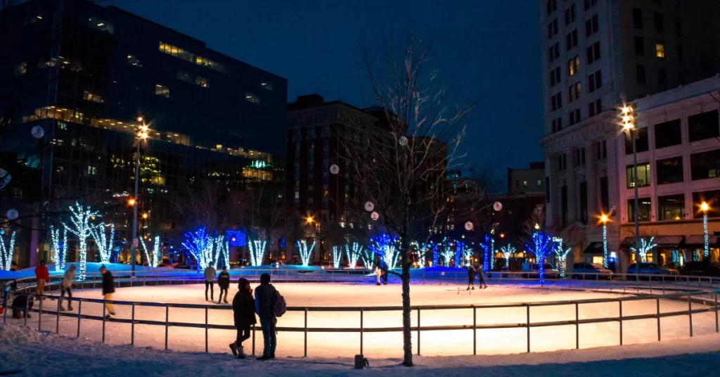 people skaing at lit up outdoor ice area at night