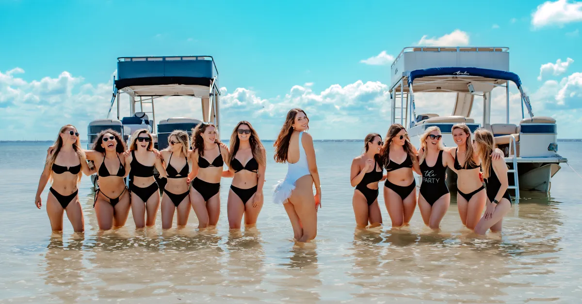 bachelorette party lined up on shoreline in front of boats