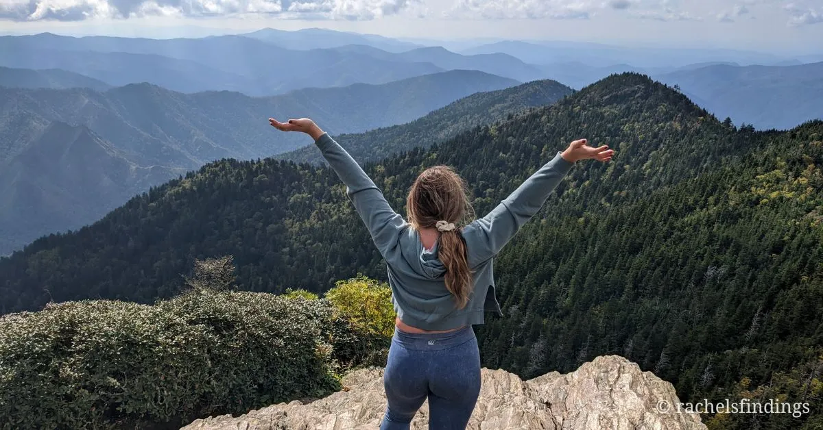 girl facing leconte mountains with hands wide above head