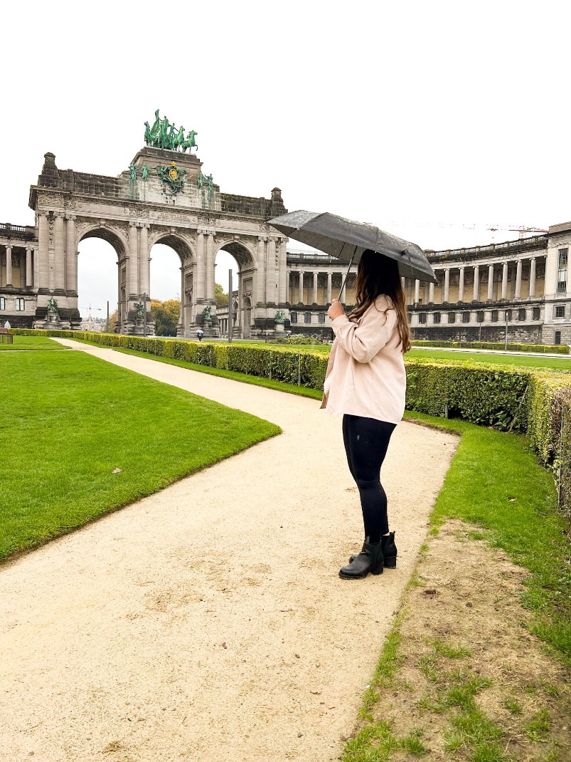 girl with umbrella standing in front of parc du cinquantenaire brussels