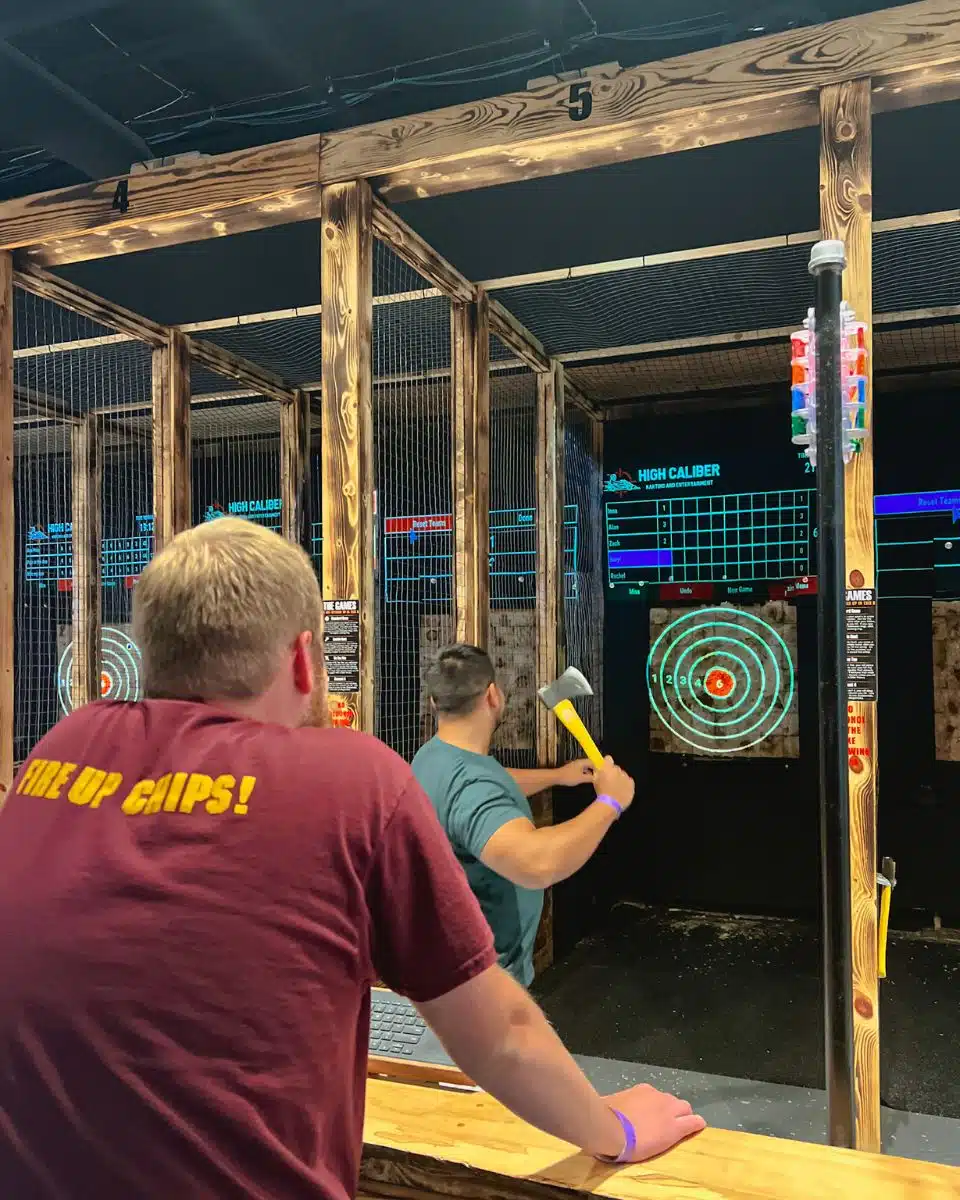 man axe throwing and male friend watching