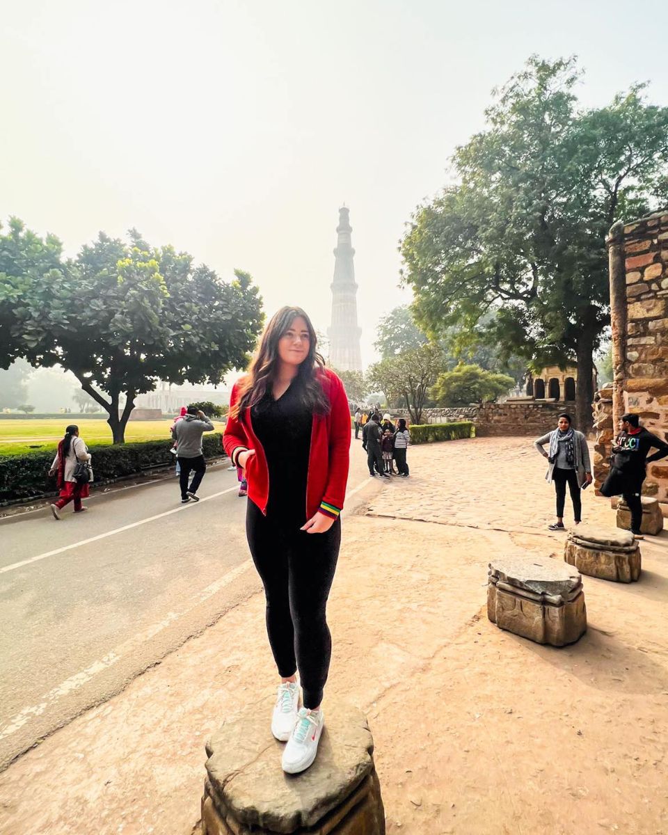 rachel hannah standing on stone with qutab minar in background